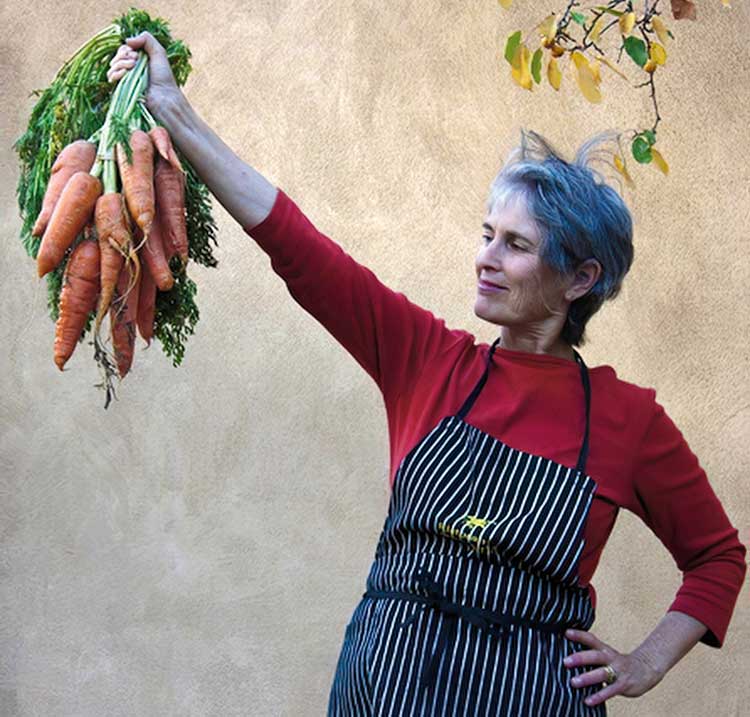 Author Deborah Madison holding a bunch of carrots