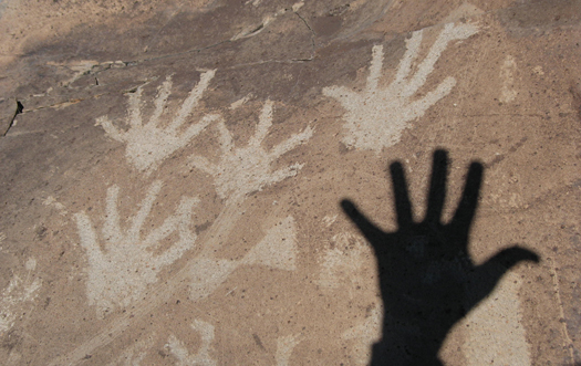 Ancient handprints with the shadow of a modern hand from the Office of Archaeological Studies.