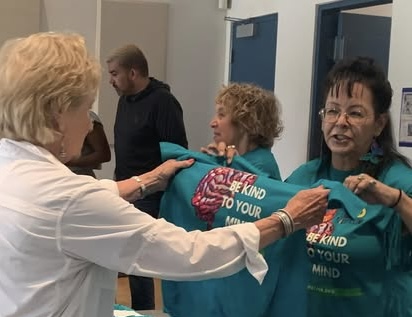 A The Life Link volunteer gives a free t-shirt to an attendee of Be Kind to Your Mind.