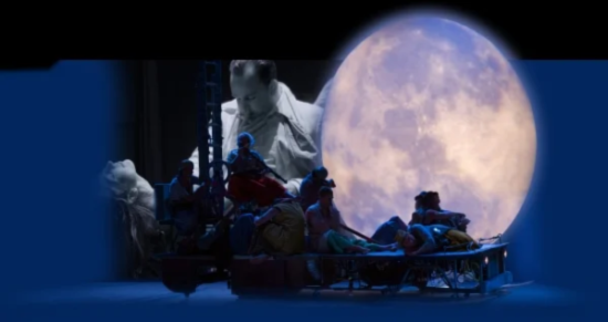 Blue-lit stage scene with a group of people on a cart, a large full moon behind them.